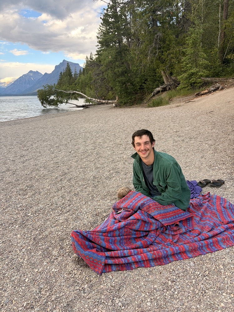 Rob, owner of Tame Dog Solutions, smiling on a lakeshore with mountains behind him