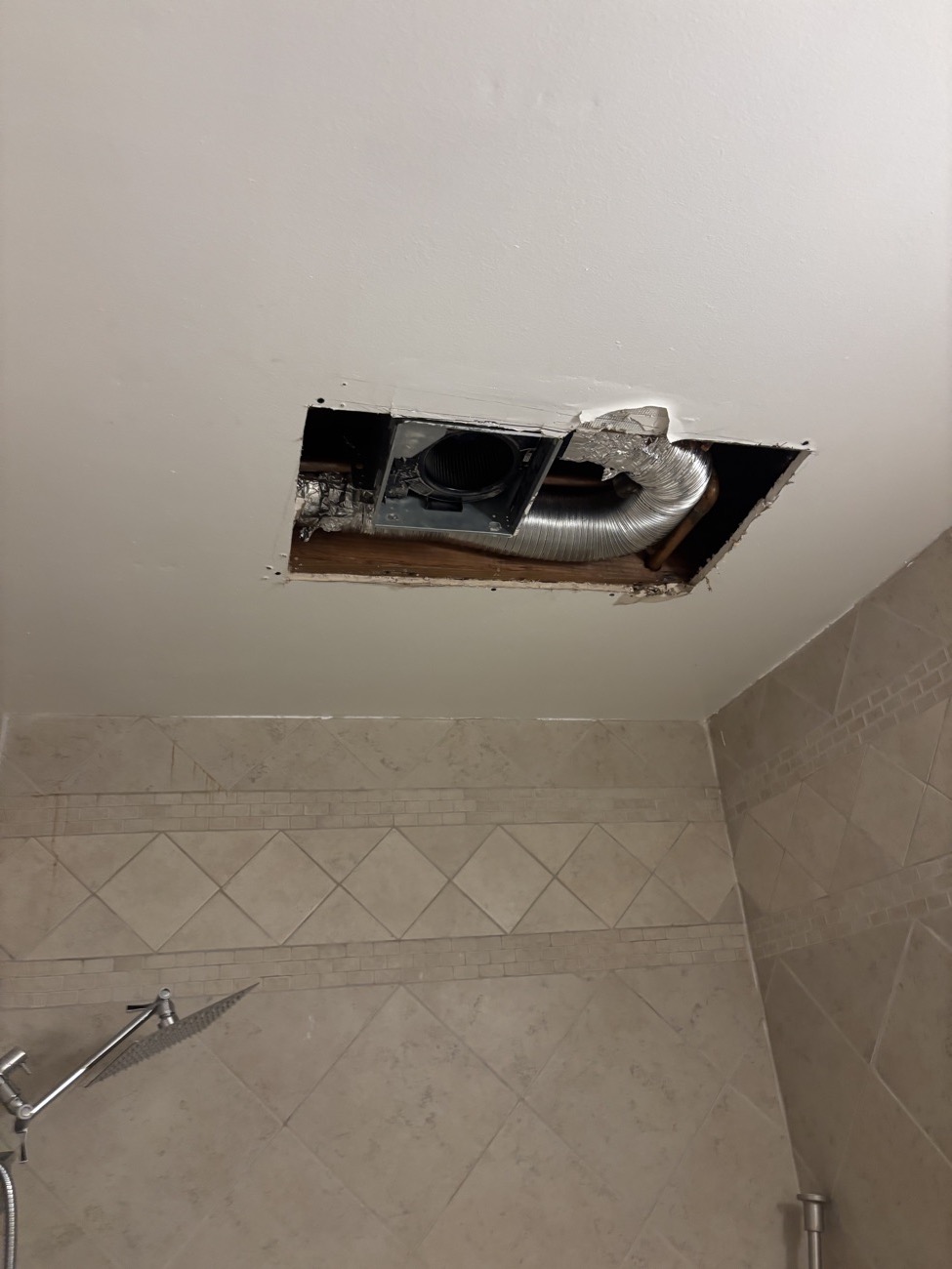 Bathroom ceiling opened up around the exhaust fan after a leak from the bathroom above