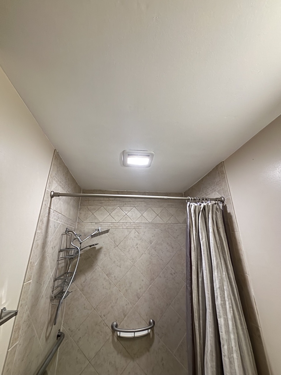 The same bathroom ceiling patched and repainted, with the exhaust fan back in place