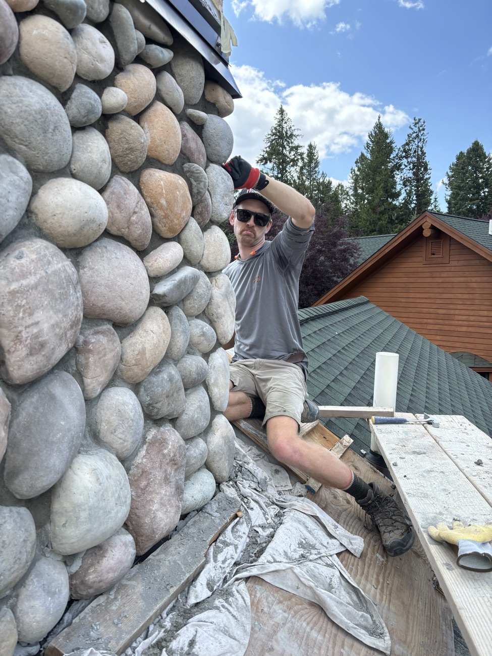 River rock chimney being finished on a rooftop