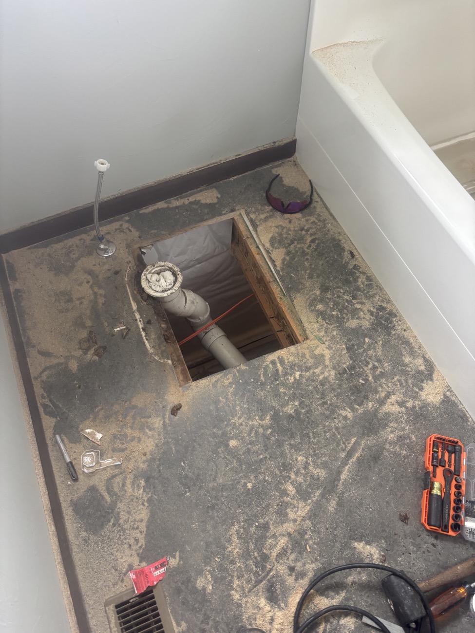 Bathroom floor with the rotted subfloor cut out around the toilet drain